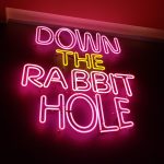 Foto eines Neon-Leutschildes, der lautet: "Down the rabbit hole"